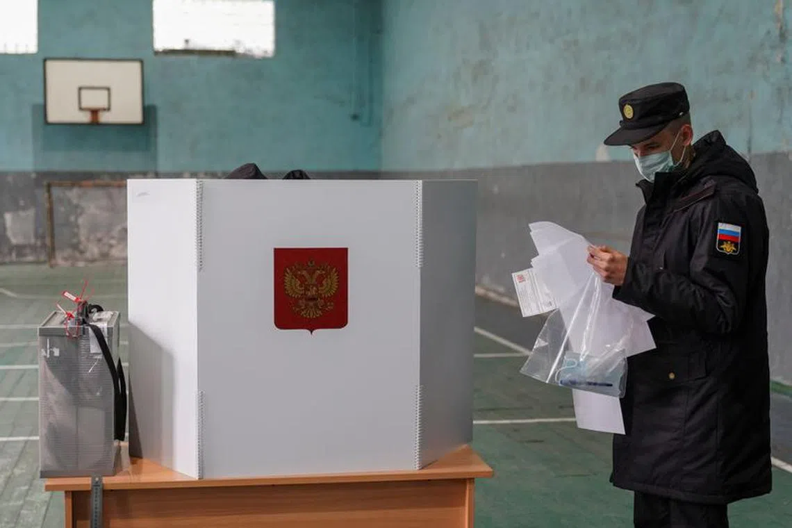 FILE PHOTO: A Russian serviceman studies ballots at a polling station, which is  placed in a sport hall, during a three-day parliamentary election in the village of Ryabinovka in Kaliningrad region, Russia September 18, 2021. REUTERS/Vitaly Nevar/File photo