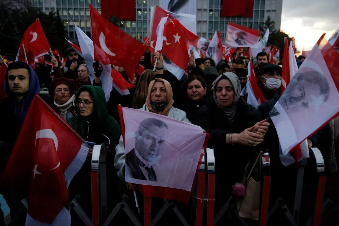 Supporters of Istanbul mayor Ekrem Imamoglu wave Turkish flags as they gather in front of his office, on Dec 14, 2022.
