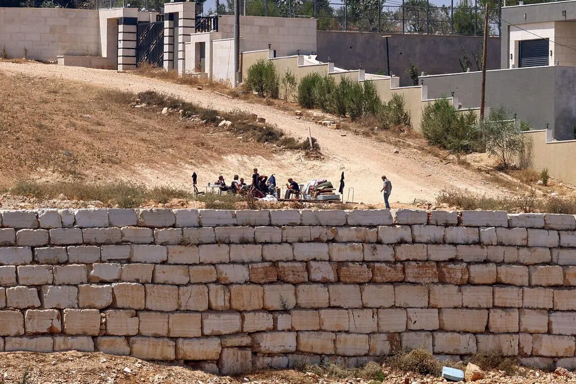 Israeli settlers gather in front of Palestinian houses in the village of Qusra, south of Nablus, in the occupied West Bank, on Aug 12.