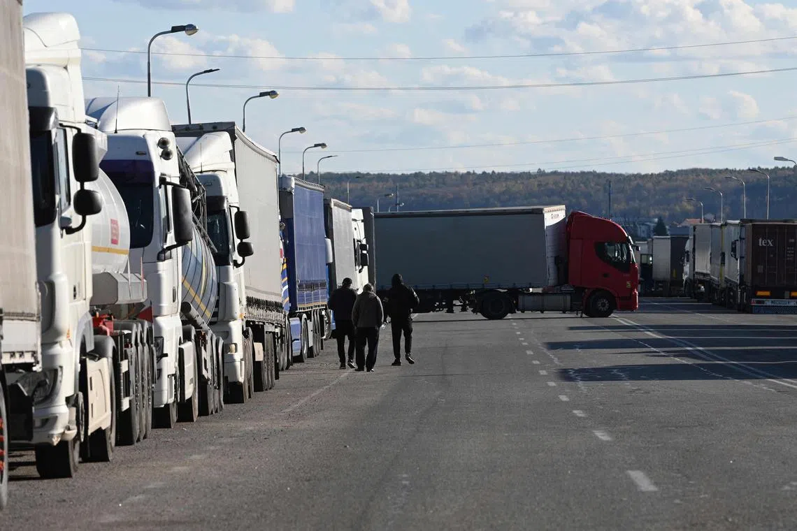 Driver walk among trucks queuing at the Rava-Ruska border checkpoint on the Ukrainian-Polish border.