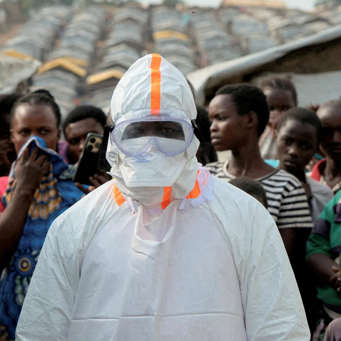 FILE PHOTO: A health worker in personal protective equipment stands near displaced people waiting for the burial of suspected Ebola victims at the Kigonze displaced persons camp, one month after an outbreak was declared, in Bunia, eastern Democratic Republic of Congo, June 18, 2026. REUTERS/Gradel Muyisa Mumbere/File Photo