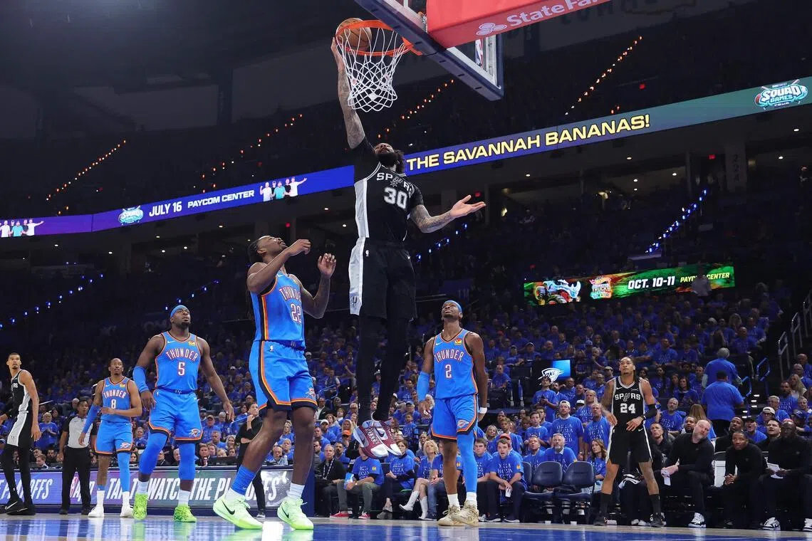Julian Champagnie of the San Antonio Spurs shoots the ball against Cason Wallace and Shai Gilgeous-Alexander of the Oklahoma City Thunder during the third quarter in Game 1.