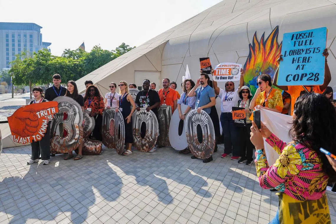 Environmental activists display placards during a demonstration at the venue of the COP28 United Nations climate summit in Dubai on December 5, 2023. The COP28 meeting is being hosted by oil-rich United Arab Emirates, which has made no secret of its plan to include fossil fuel interests and has boosted overall attendance to more than 80,000, making this year's meeting the largest COP. (Photo by Giuseppe CACACE / AFP)