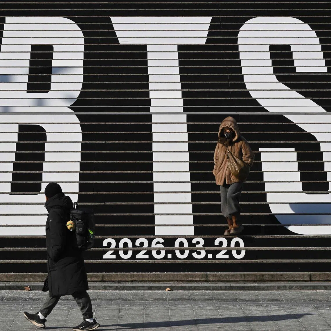 (FILES) Pedestrians walk along the stairs displayed with the BTS logo and release date of BTS' 2026 album at Gwanghwamun Square in Seoul on January 14, 2026. Mexico's President Claudia Sheinbaum declared on January 26, 2026, that "nearly a million young people" had vied for one of the coveted 150,000 tickets to K-pop megastars BTS's Mexican gigs and said she wrote to South Korea's President Lee Jae Myung to ask that he "bring the acclaimed K-pop artists more often" to her country. Sheinbaum said she had also asked Ocesa, the promoter of the shows in Mexico, about the possibility of organizing more dates, but received a negative answer. BTS will perform three dates in Mexico City in May 2026. (Photo by Jung Yeon-je / AFP)