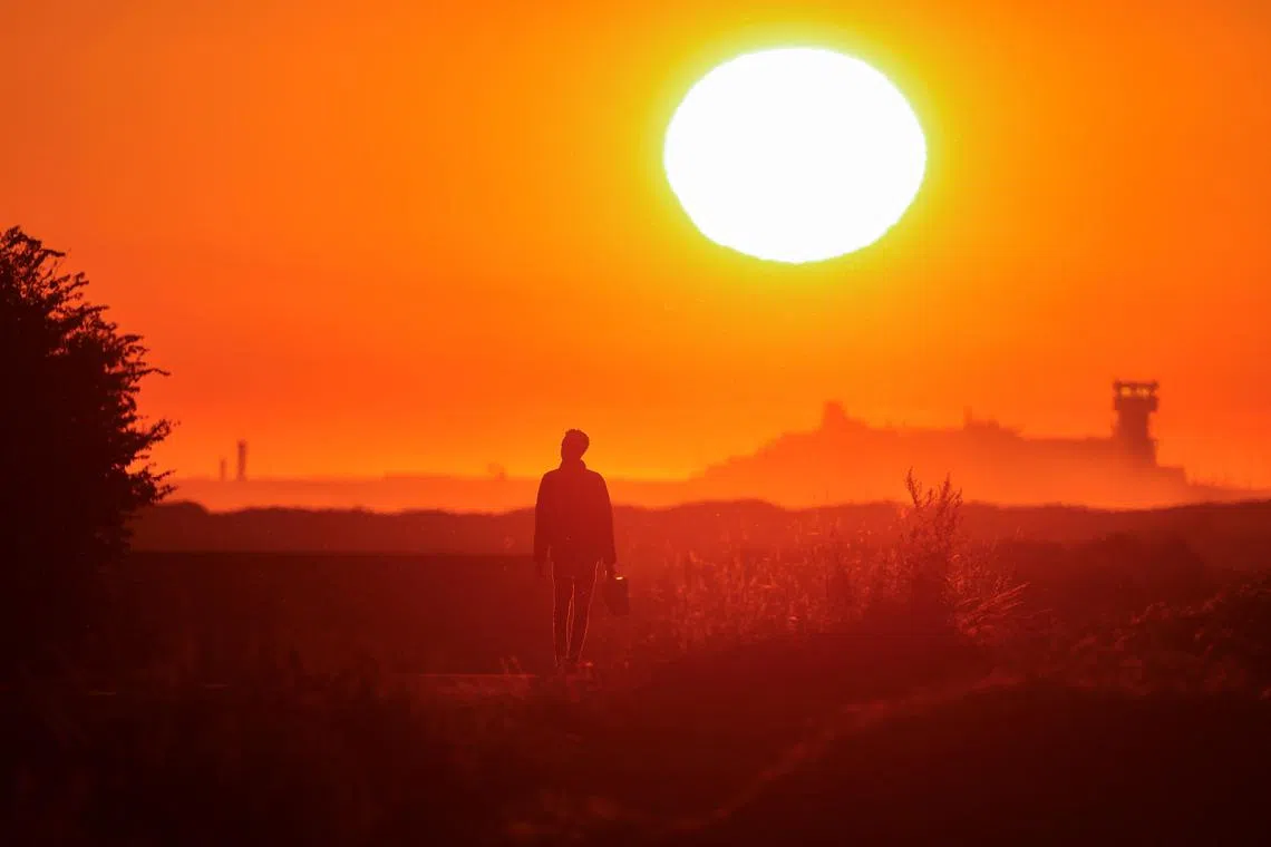 A migrant walks back to his makeshift camp at sunrise after a failed attempt to cross the Channel to the UK on a small boat, in Sangatte, France. 