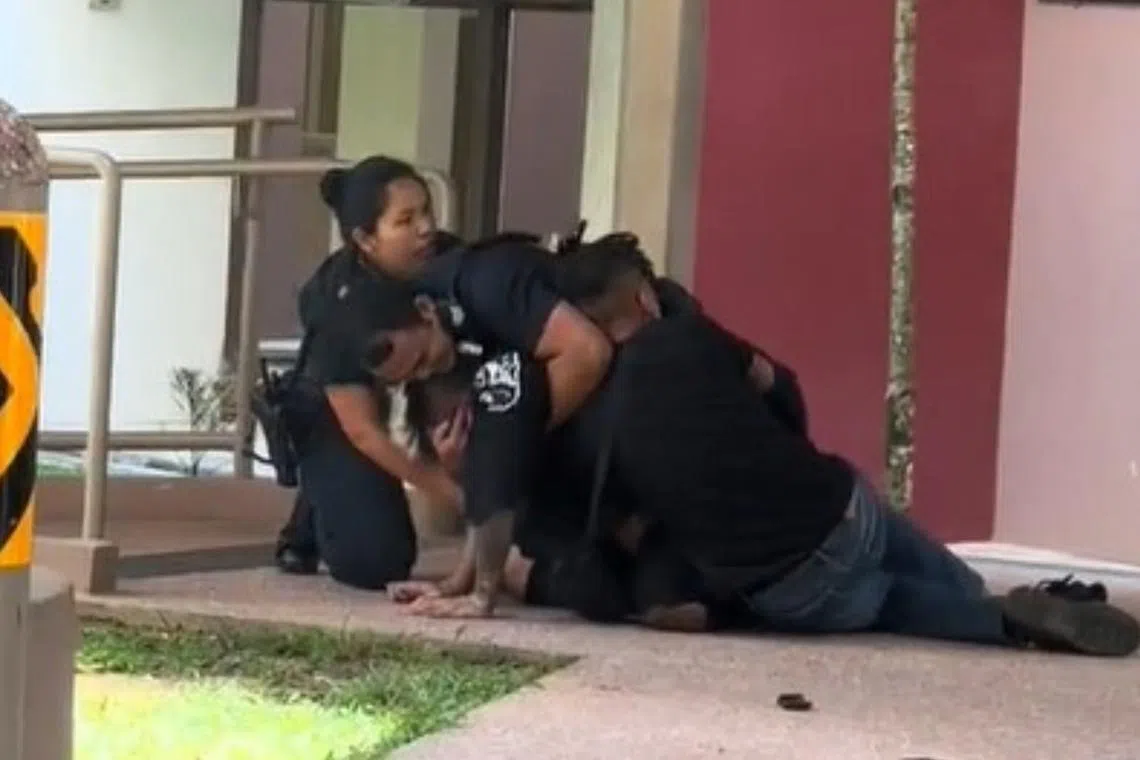 In the video, two police officers, one male and one female, can be seen trying to subdue a man on a sheltered walkway.