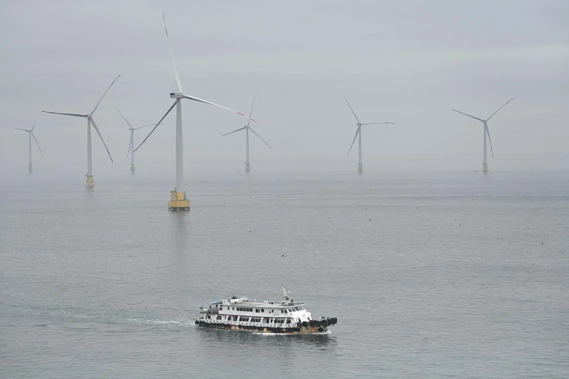 A boat passes wind turbines at the northern end of Pingtan island, the closest point in China to Taiwan’s main island, in southeast China’s Fujian province on May 24, 2024. China on May 23 encircled Taiwan with naval vessels and military aircraft in war games aimed at punishing the self-ruled island after its new president vowed to defend democracy. (Photo by Greg Baker / AFP)