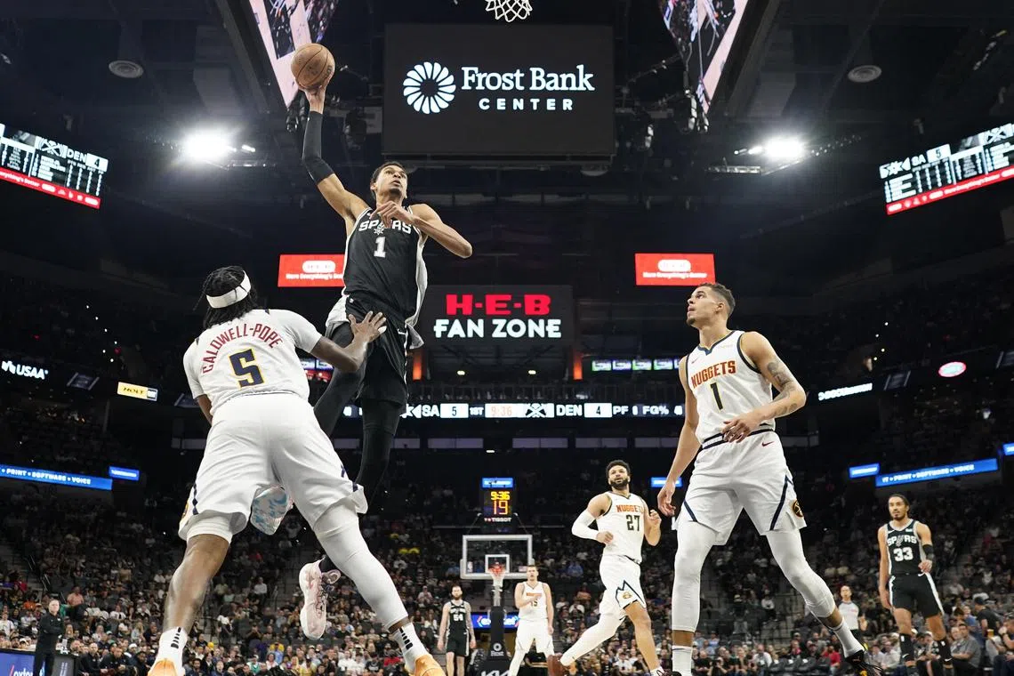 San Antonio Spurs forward Victor Wembanyama goes up to dunk over Denver Nuggets guard Kentavious Caldwell-Pope and forward Michael Porter Jr. during the first half at Frost Bank Centre.