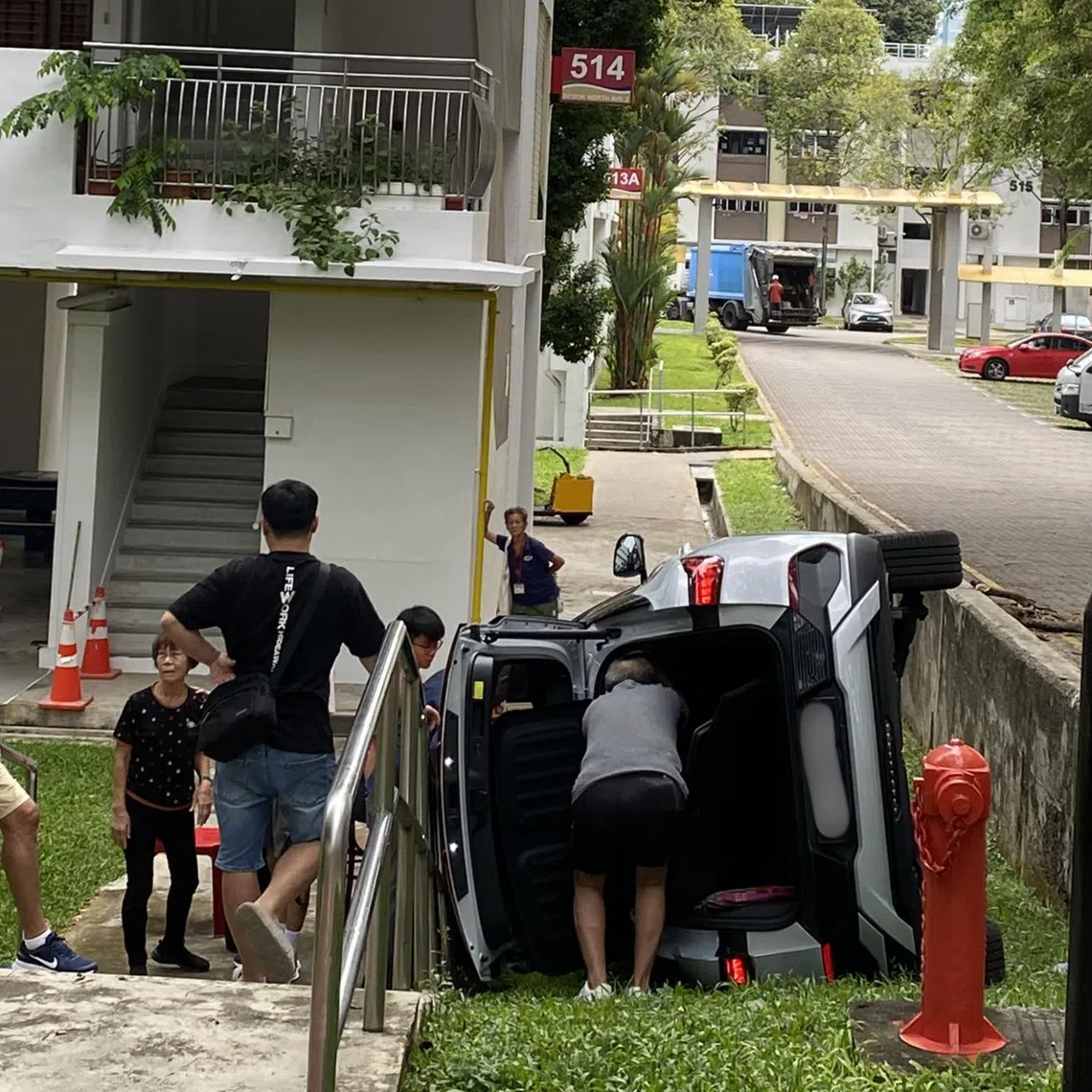 A car is seen on its left side on a patch of grass near Block 514 Bedok North Avenue 2.