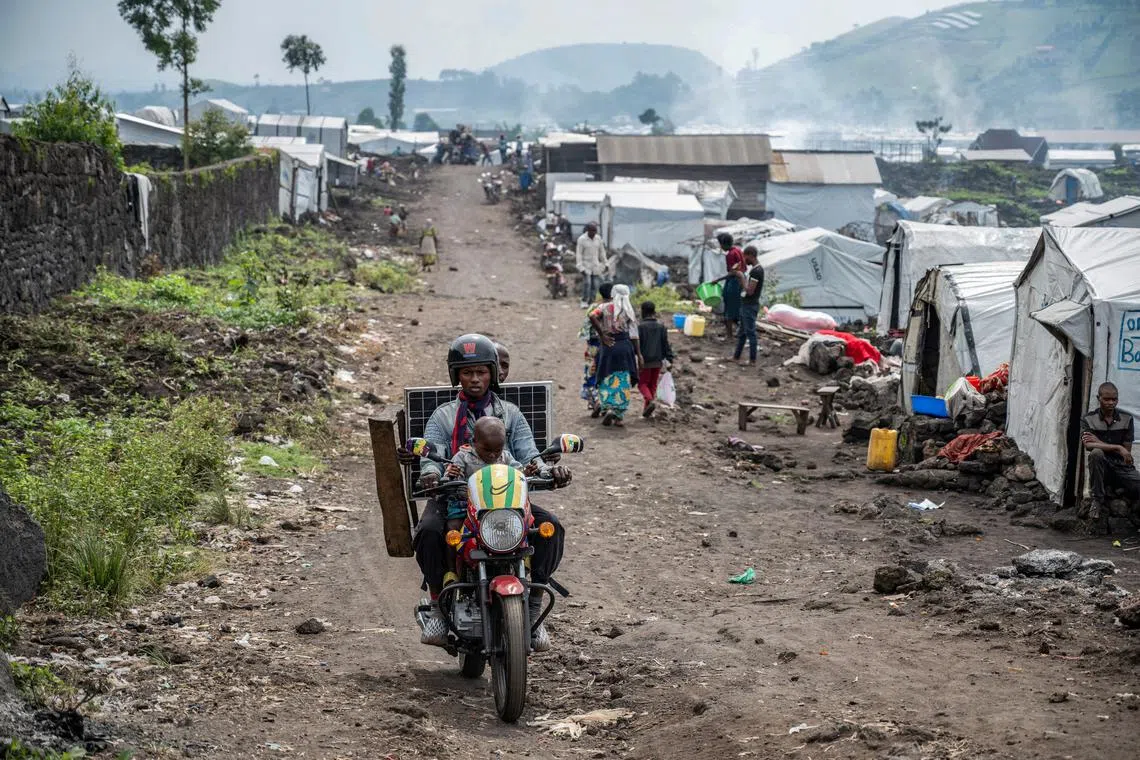 FILE PHOTO: People ride past Congolese people, displaced by recent clashes between the M23 rebels and the Armed Forces of the Democratic Republic of the Congo (FARDC), as they prepare to leave the camp after being instructed by the M23 rebels to vacate the camps on the outskirts of Goma, Democratic Republic of the Congo February 12, 2025. REUTERS/Stringer/File Photo