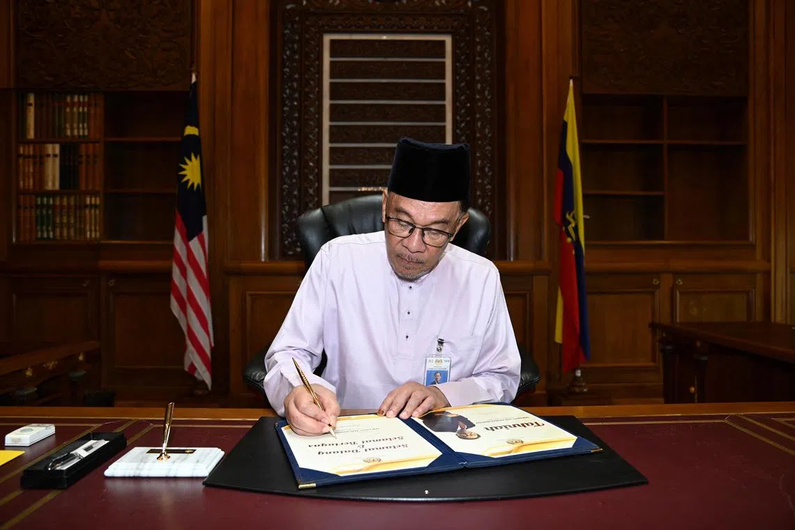 Malaysia's newly appointed Prime Minister Anwar Ibrahim signing a document as he clocks in to the Prime Minister office on his first day holding the premier position at Putrajaya, Malaysia November 25, 2022. Malaysian Department of Information/Wazari Wazir/Handout via REUTERS ATTENTION EDITORS - THIS IMAGE HAS BEEN SUPPLIED BY A THIRD PARTY. NO RESALES. NO ARCHIVES. MANDATORY CREDIT 
