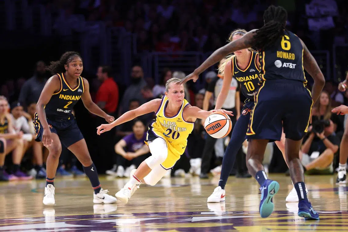 Aari McDonald, Natasha Howard and Lexie Hull of the Indiana Fever defend against the dribble of Julie Allemand of the Los Angeles Sparks.