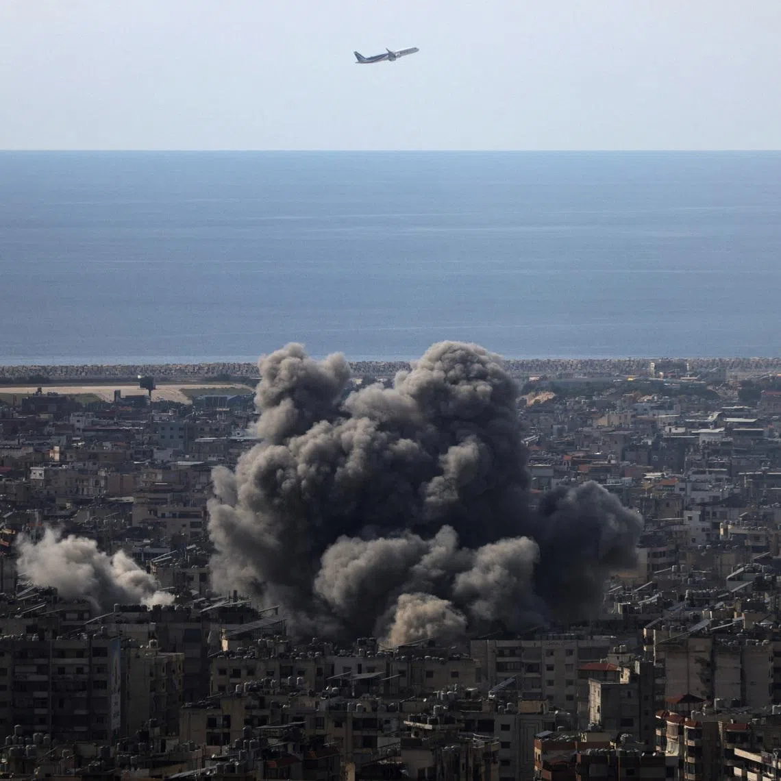 An airplane flies as smoke rises after an Israeli strike on Beirut's southern suburbs, following an escalation between Hezbollah and Israel amid the U.S.-Israeli conflict with Iran, Lebanon, March 6, 2026. REUTERS/Khalil Ashawi