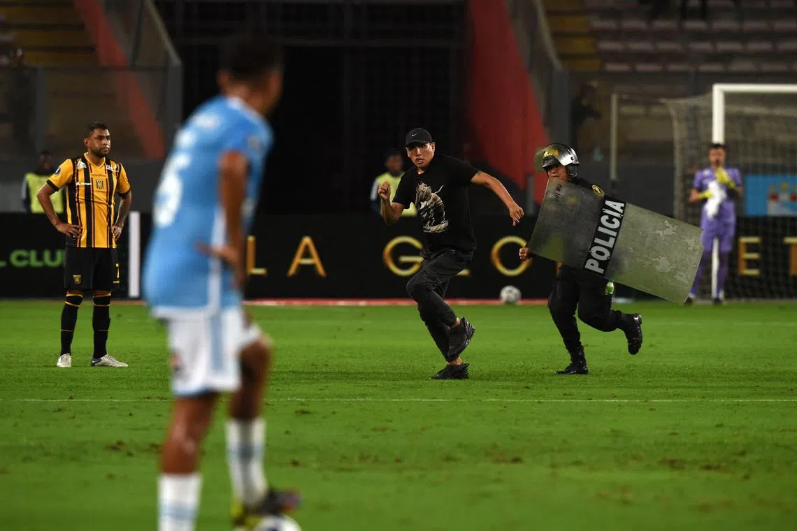 A pitch invader running to evade a police officer during the Copa Libertadores group stage first leg football match between Peru's Sporting Cristal and Bolivia's The Strongest, at the National stadium in Lima on May 2, 2023. 