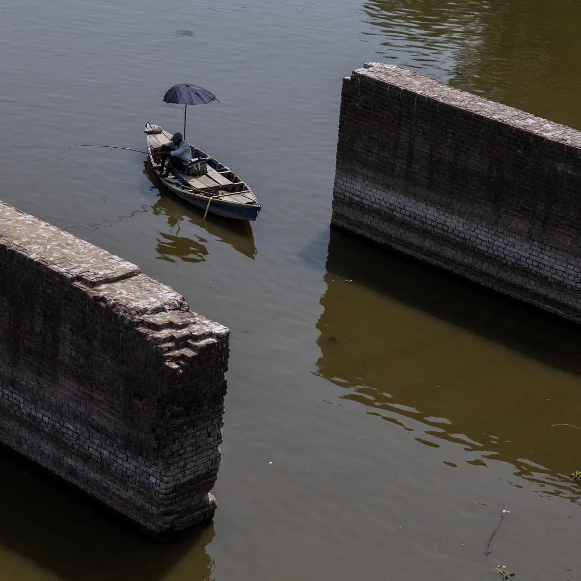 FILE PHOTO: A man catches fish as sits in his boat in the river Yamuna on a hot summer day in New Delhi, India, June 11, 2026. REUTERS/Adnan Abidi/File Photo