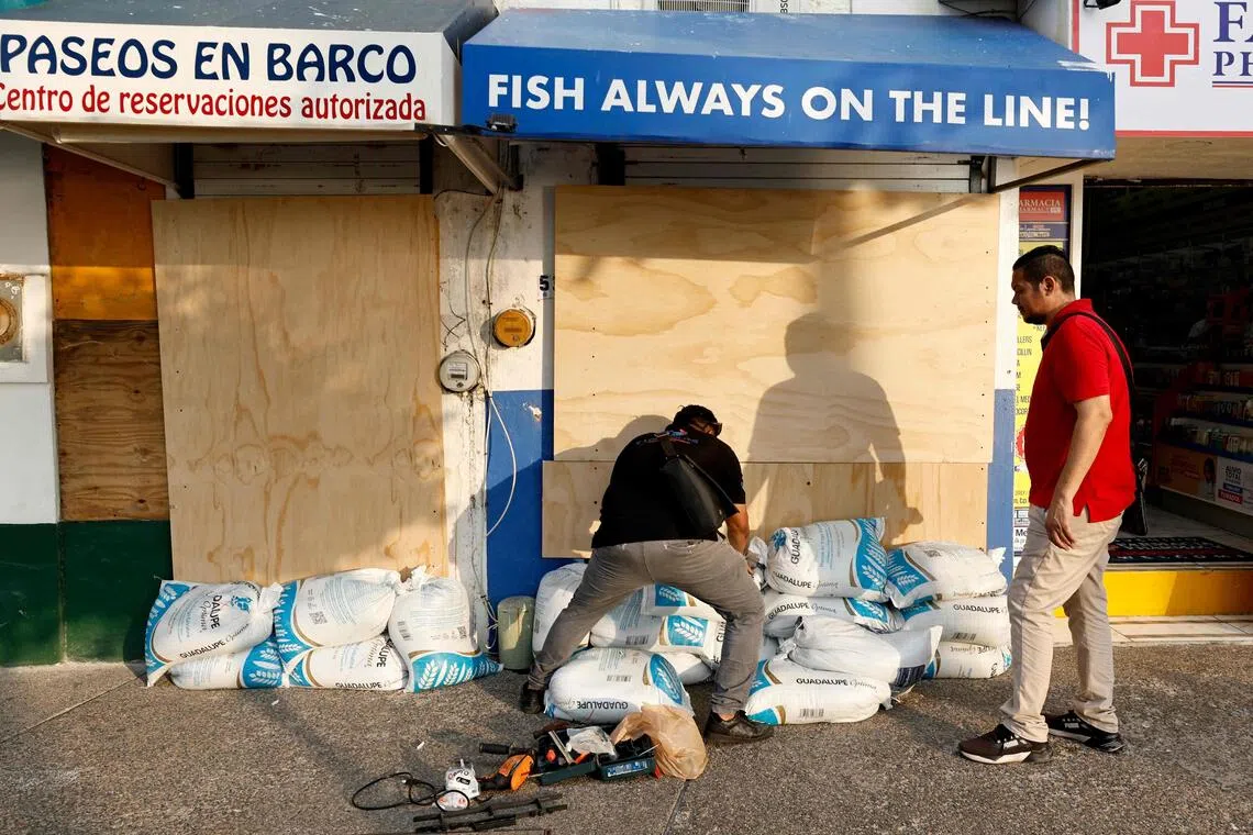 People in Puerto Vallarta, in Mexico’s Jalisco state, protecting their businesses from the potential impact of Hurricane Simon on Oct 9.