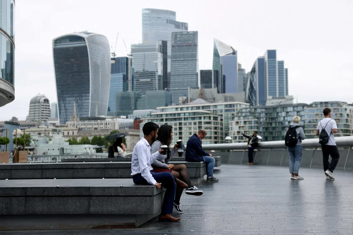 People drink takeaway coffee in view of the City of London skyline in London, Britain, July 25, 2024. REUTERS/Hollie Adams/File Photo