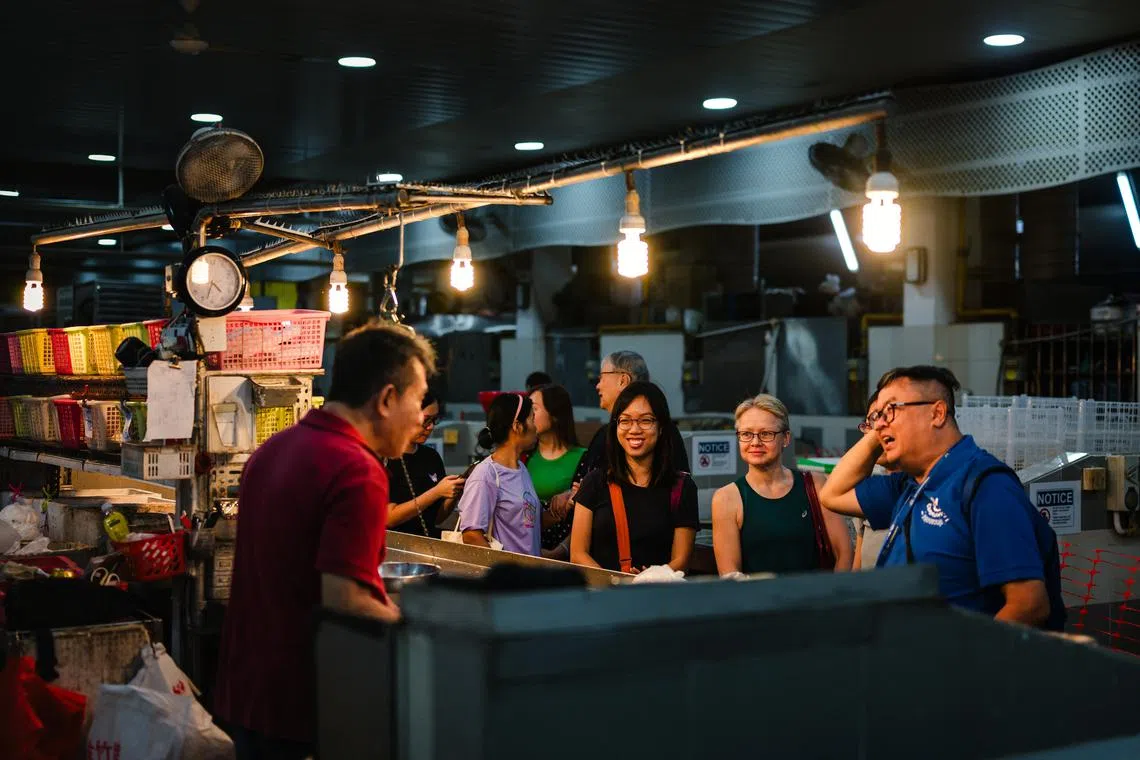 Tour participants speaking to a fishmonger at Tanglin Halt Market in the early hours of Sunday morning. 