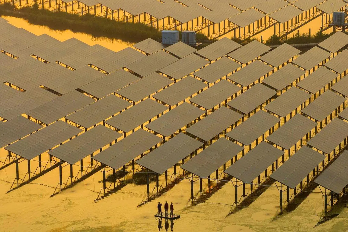 Workers inspecting solar panels at the fishing-solar complementary photovoltaic power generation base in  Taizhou, in China’s eastern Jiangsu province on July 12, 2023. 