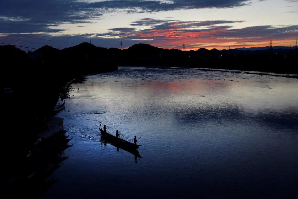 Cormorant fishing master, known as usho, Youichiro Adachi, 48, his son Toichiro, 22, and his steersman Naoki Adachi, 44, sailing for cormorant fishing, known as ukai, on the Nagara River in Oze, Seki, Japan, Sept 9, 2023.
The sand and gravel has increased, and along with that the ayu have gotten smaller too."  