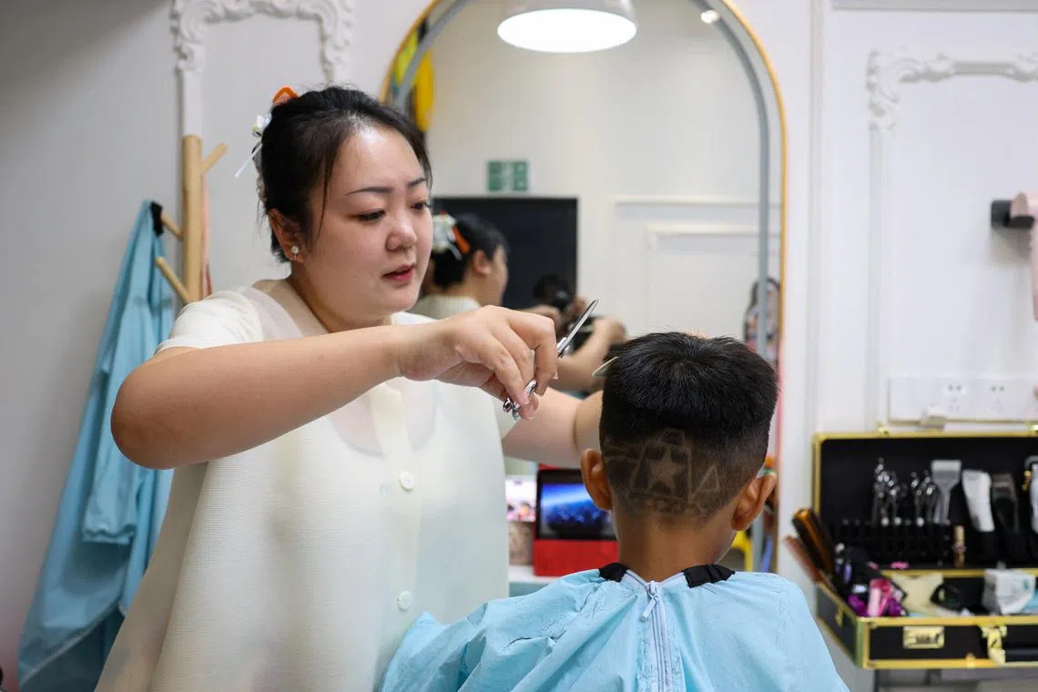 Hair salon owner Wang Xueru gives a child a haircut in a design of a tank to commemorate the 80th anniversary of the end of World War Two, at her store in Beijing, China August 28, 2025. REUTERS/Tingshu Wang