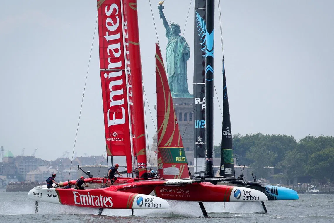 SailGP F50 team Emirates GBR skippered by Giles Scott rounds a mark with team New Zealand skippered by Peter Burling in front of the Statue of Liberty.