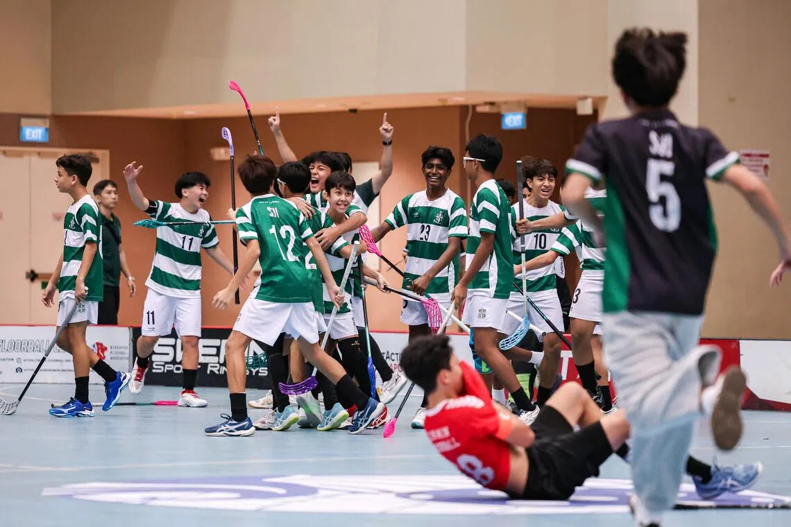 St Joseph’s Institution players celebrating after the final whistle as Xinmin Secondary School captain Firhan Hafiz lies on the floor in dejection during the National School Games C Division boys’ floorball final.