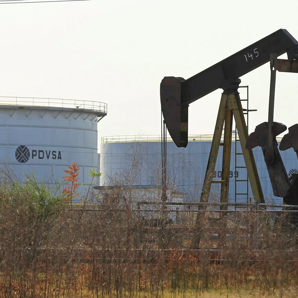 An oil pumpjack and a tank with the corporate logo of state oil company PDVSA are seen in an oil facility in Lagunillas, Venezuela January 29, 2019. REUTERS/Isaac Urrutia