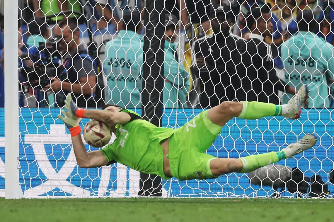 Argentina's Emiliano Martinez saves a penalty taken by France's Kingsley Coman during the penalty shootout.