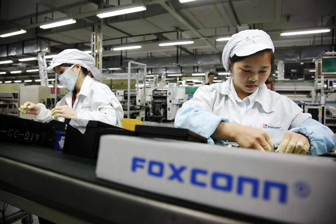Employees work on the assembly line at Taiwanese manufacturer Foxconn's plant in Shenzhen, China. A growing wave of Taiwanese companies that rode the tide of cheap manufacturing in China over the last three decades are returning home as costs on the mainland creep up.