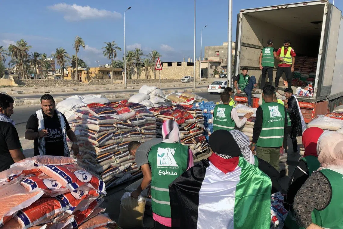 People load a humanitarian aid convoy for the Gaza Strip, parked in Arish, Egypt, on Oct 16, 2023.