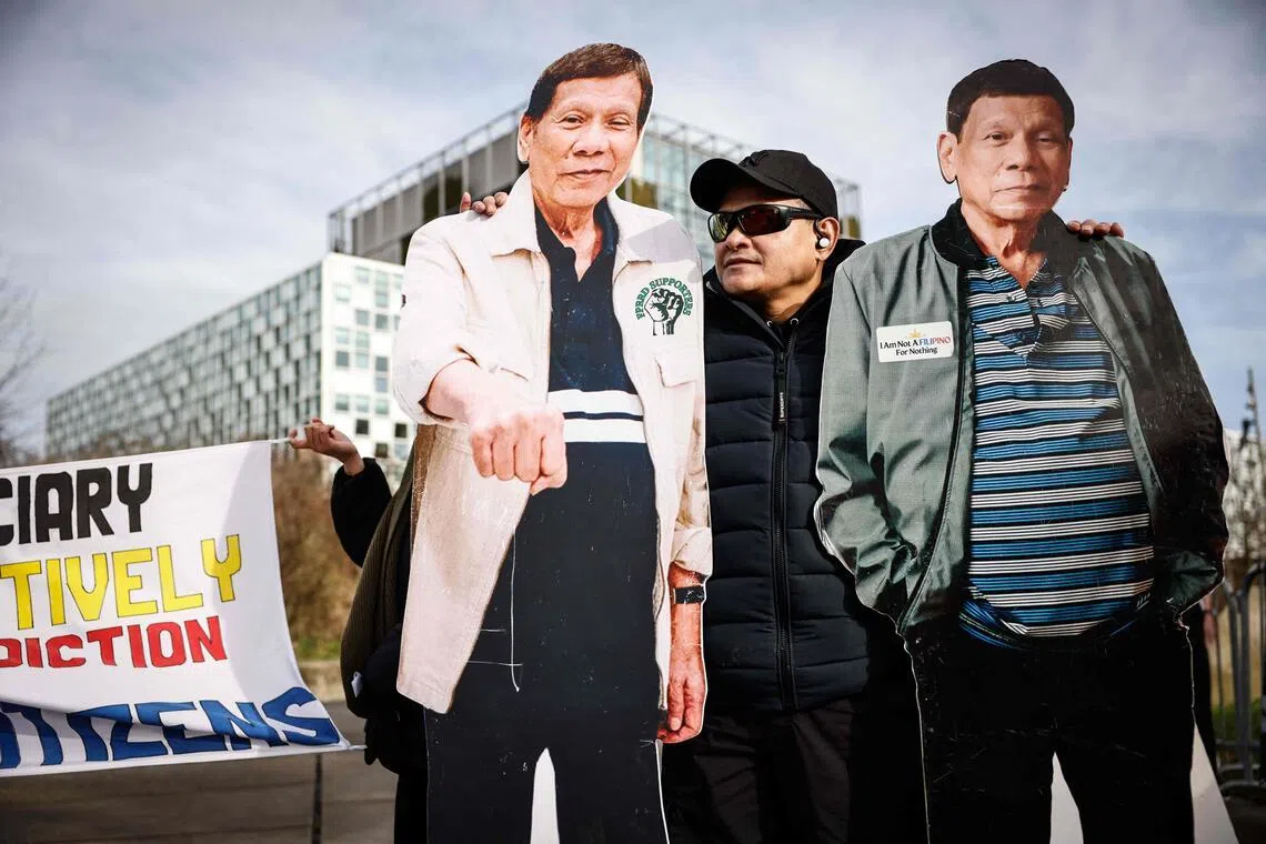 A person stands by two life-size cutouts of former Philippines' president Rodrigo Duterte during a demonstration in his support outside the International Criminal Court (ICC) on Feb 23, 2026.