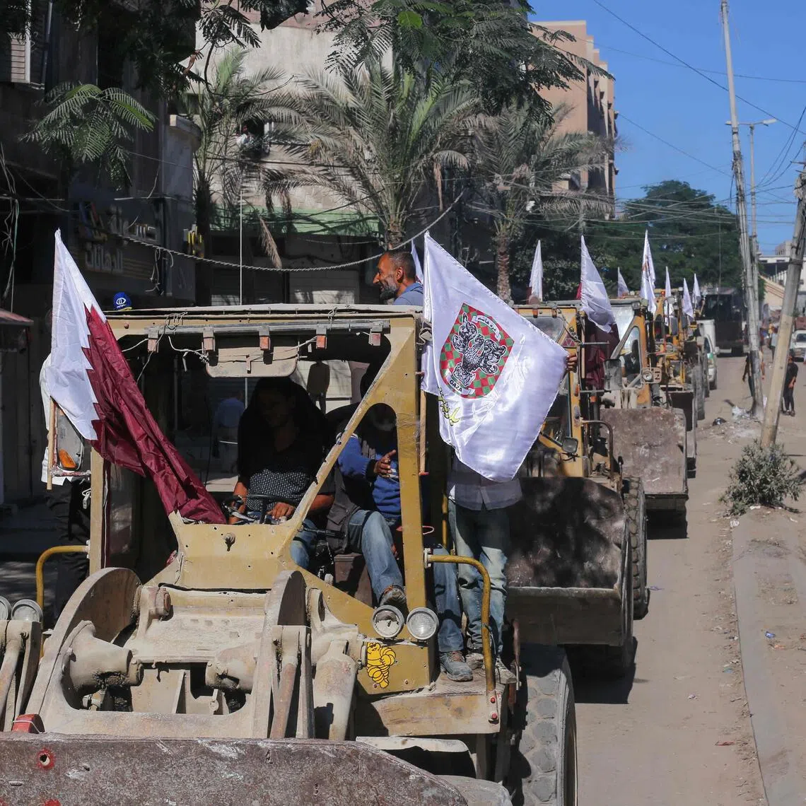 Bulldozers deployed by the Gaza Municipality drive past Palestinians on the way to clear building rubble from main axes and streets in Gaza City on Oct 14.