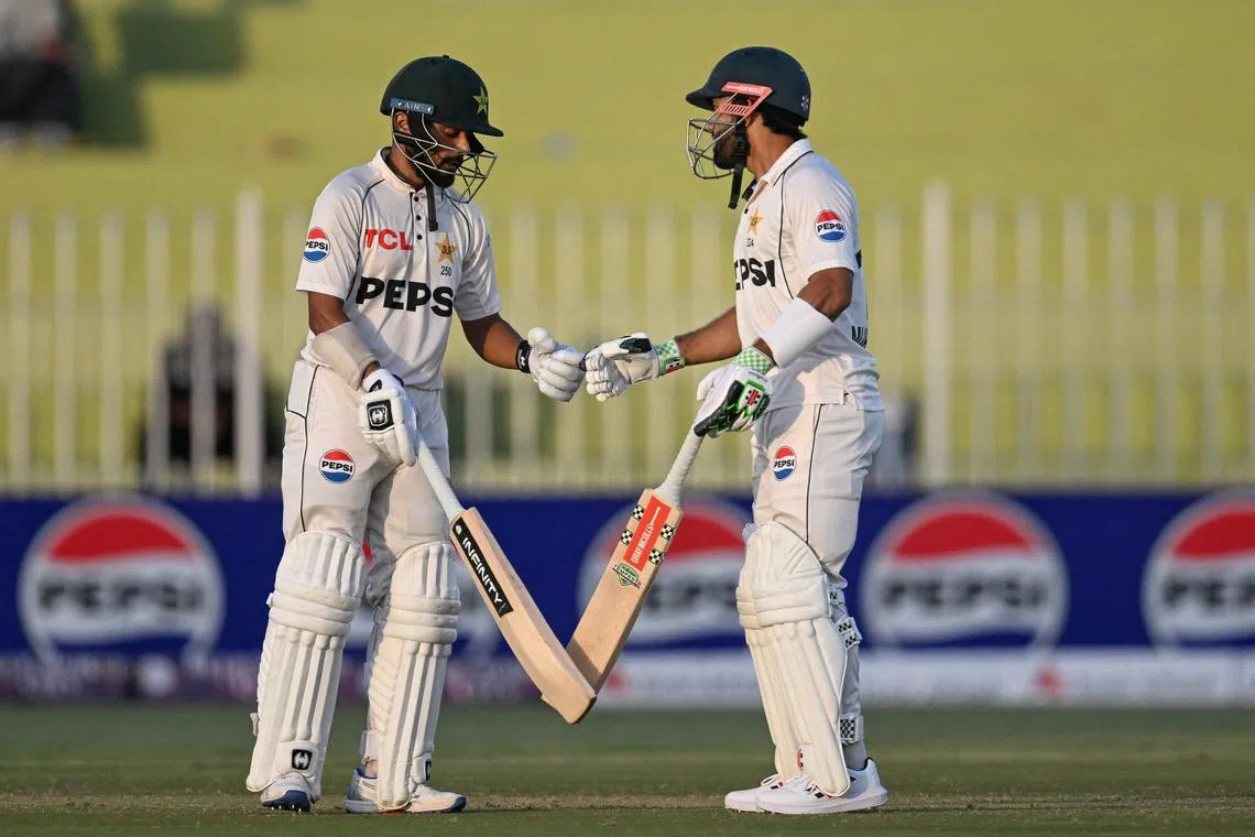 Pakistan's Saud Shakeel (eft) celebrates with teammate Mohammad Rizwan after scoring a half-century on the first day of the first Test against Bangladesh at the Rawalpindi Cricket Stadium on Aug 21, 2024.