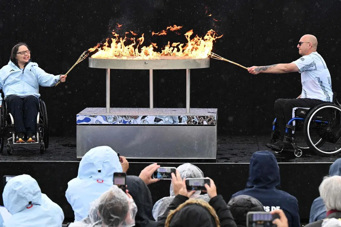 Britain's Helene Raynsford and Gregor Ewan light the Olympic cauldron during the Paralympic torch-lighting ceremony at Stoke Mandeville in Aylesbury, central England on August 24, 2024. Four days before the Paris Paralympic Games begins, the Paralympic flame was lit on Saturday next to the English hospital where the idea for the competition was born. The Paralympic movement dates back to 1948, when German neurologist Ludwig Guttmann organised sporting events for injured veterans at Stoke Mandeville Hospital, northwest of London. The flame will pass through the Channel Tunnel on Sunday, with 24 British torchbearers taking it halfway, before handing it over to 24 French torchbearers, who will take it to Calais. (Photo by JUSTIN TALLIS / AFP)