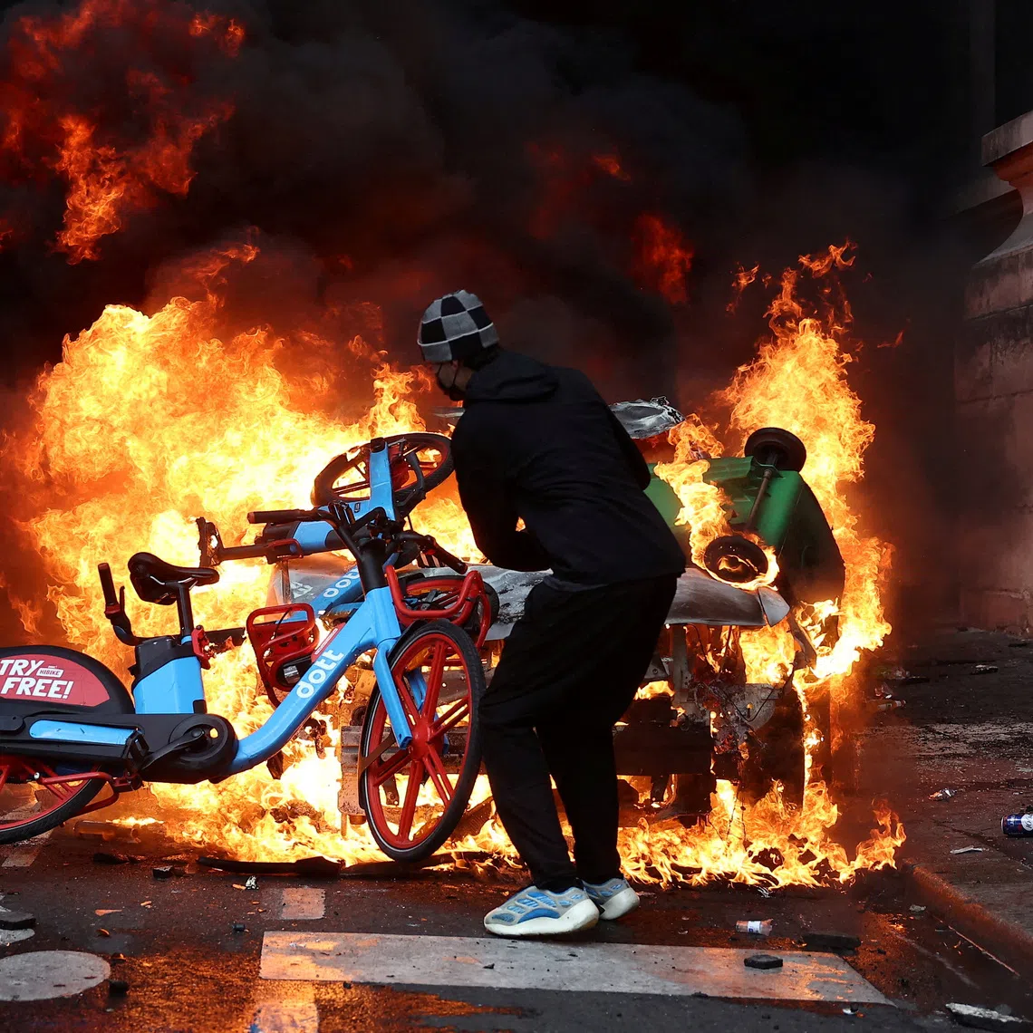 FILE PHOTO: A protester throws a bicycle onto a burning car amid clashes during a day of demonstrations against the cost of living and rising fuel prices in Paris as part of nationwide protests called by the \"Yellow Vests\" movement, joined by French high school and university students, teachers and parents demanding better school conditions and government action, as well as labour unions, workers, farmers and retirees, France, October 17, 2026.   REUTERS/Abdul Saboor/File Photo