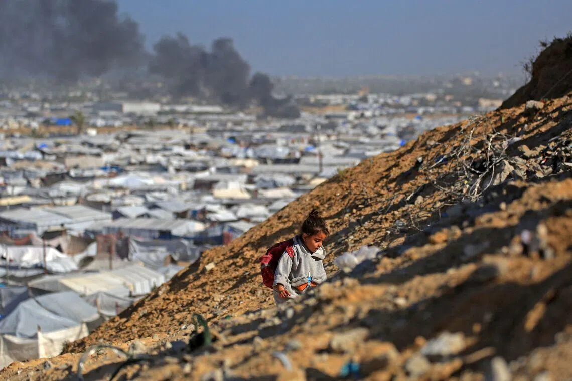 A girl climbing a hilltop against the backdrop of smoke rising from the Gath shelter, that houses displaced Palestinians, after an Israeli air strike in the west of Khan Yunis, southern Gaza Strip on Jan 31, 2026. Israeli air strikes killed 11 people in the Gaza Strip on Jan 31.