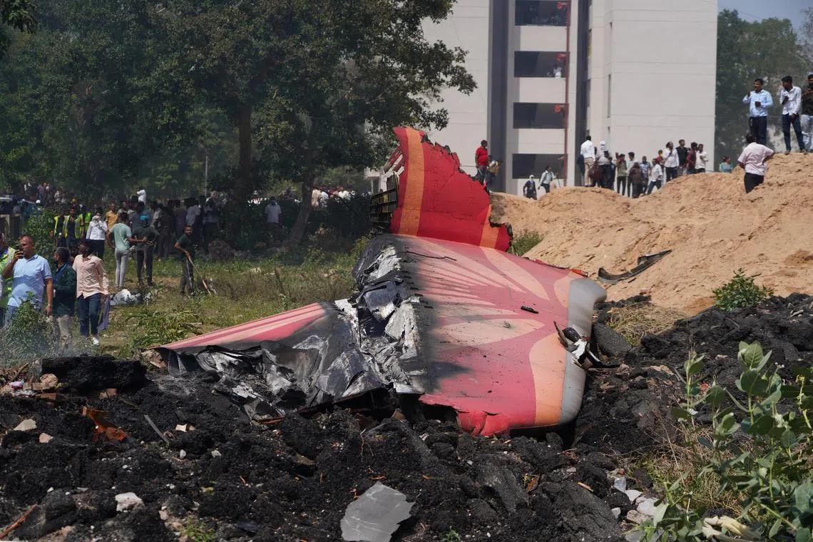 People standing near debris at the site of a plane crash near Sardar Vallabhbhai Patel International Airport in Ahmedabad, Gujarat, western India, on  June 12, 2025. 