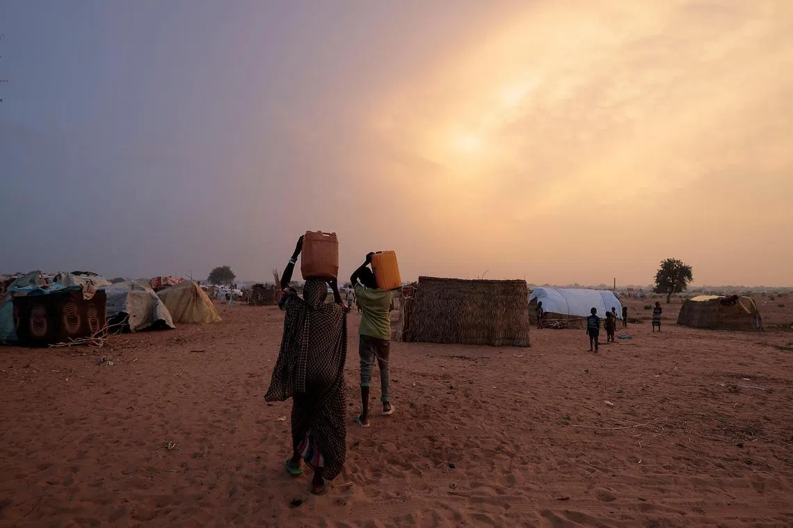 Sudanese refugees from the Darfur region carrying jerrycans of water as they walk towards their makeshift shelters in Adre, Chad. The war, which broke out in the capital Khartoum on April 15 and spread to Darfur later that month, has left at least 3,000 dead across Sudan, according to conservative estimates.  REUTERS