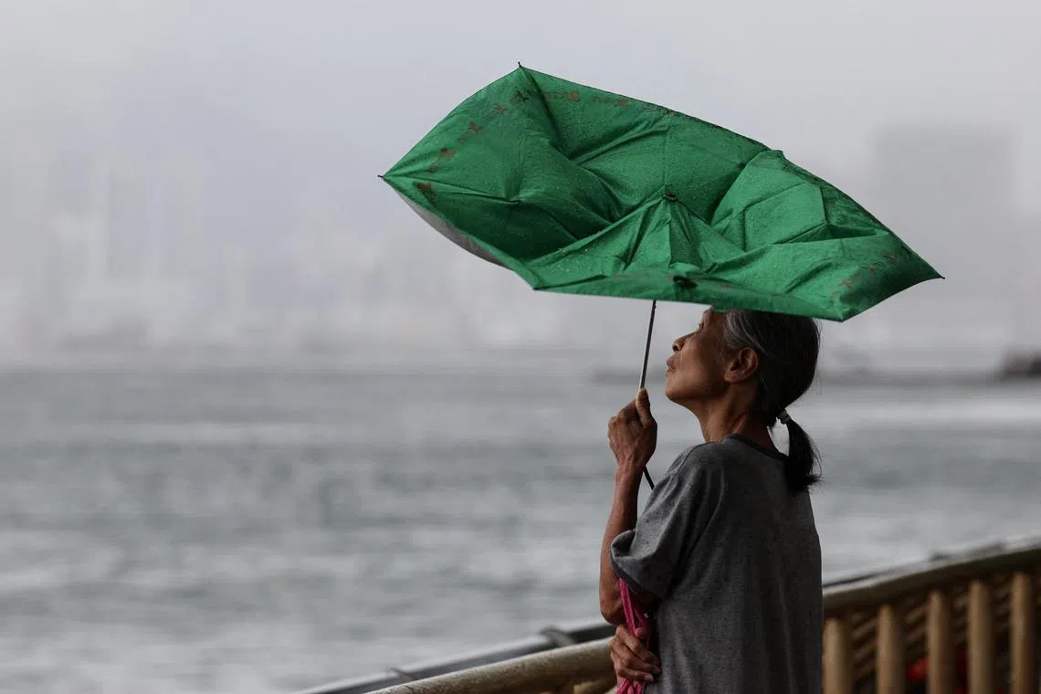 A woman holds an umbrella inverted by winds as Tropical Storm Tapah approaches in Hong Kong.