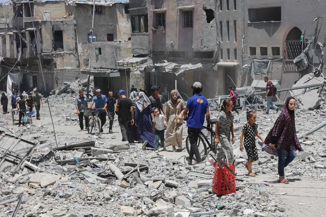 Palestinians walk on the rubble of buildings destroyed in Israeli strikes on Al-Daraj neighbourhood in Gaza City, on July 16.