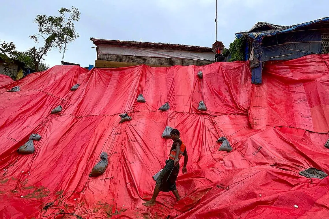 A Rohingya volunteer covering a landslide affected area with tarpaulin at the Balukhali refugee camp in Ukhia at Bangladesh's Cox's Bazar, on June 19, 2024. 