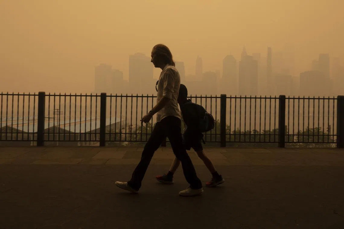 Pedestrians walk amid heavy smoke from wildfires in Canada on the Brooklyn Heights promenade in New York on Wednesday, June 7, 2023. CanadaÕs devastating fires and toxic smoke might not recur every year, but the heat from climate change increases the risks of a wide range of disasters.  (Earl Wilson/The New York Times)