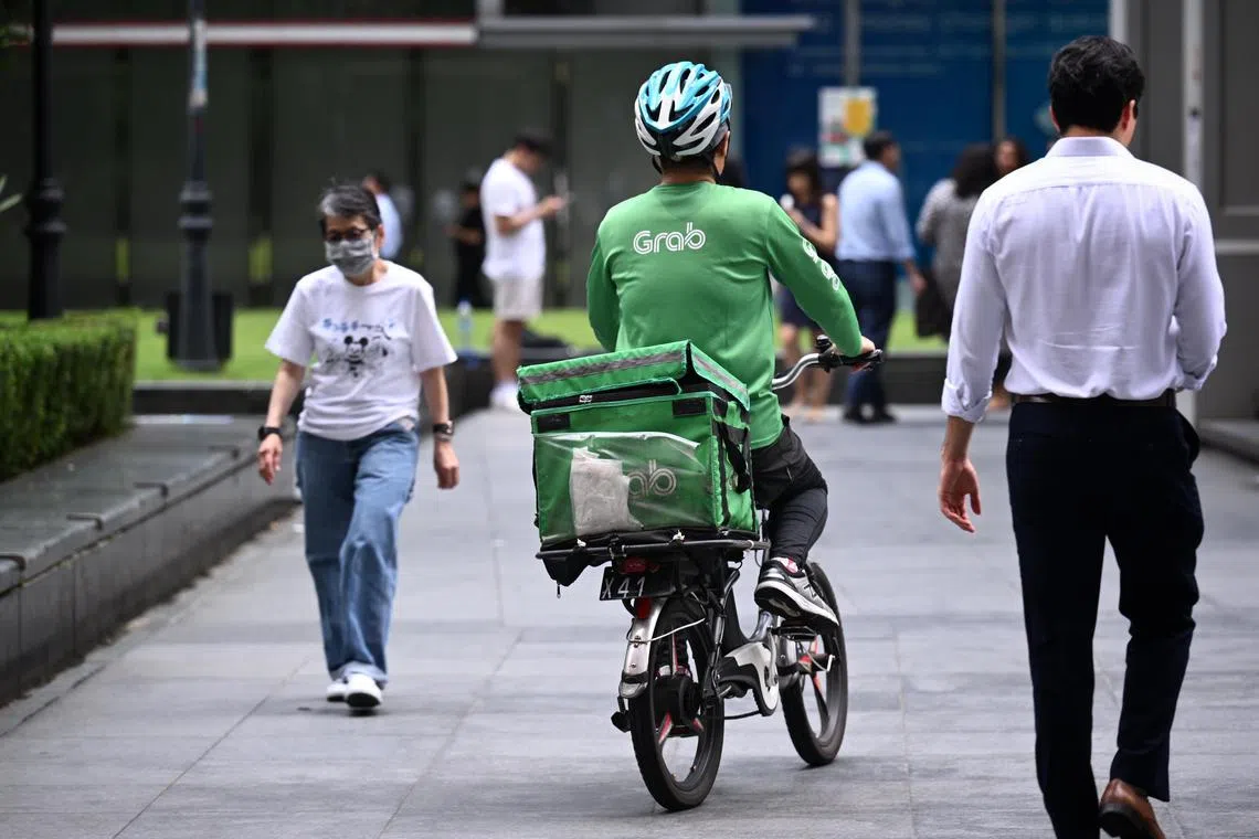 Generic photo of GrabFood delivery worker cycling in Raffles Place taken on April 22, 2024. 
Can be used for food delivery, cyclist safety, labour, manpower, PMET, stories