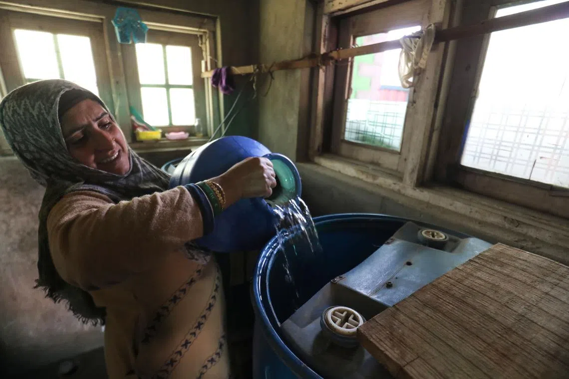 A Kashmiri woman filling a water storage from a pot with water fetched from a river, in the village of Pattan, some 22 km north of Srinagar, Kashmir, India, March 18, 2024.