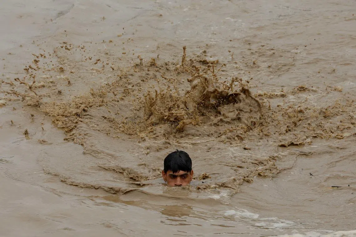 A man swims in flood waters during the monsoon season in Charsadda, Pakistan, in August 2022. There are no official guidelines for what activities count as climate finance.