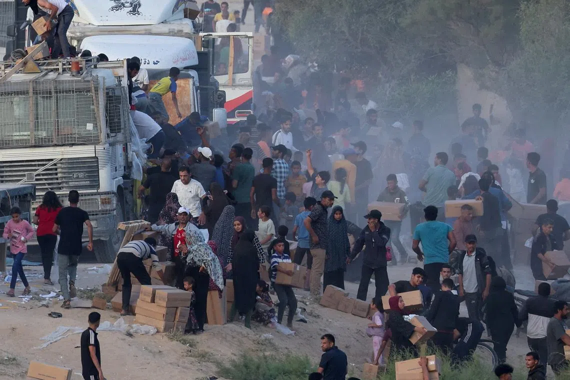 FILE PHOTO: Palestinians climb onto trucks to grab aid that was delivered into Gaza through a U.S.-built pier, amid the ongoing conflict between Israel and the Palestinian Islamist group Hamas, as seen from central Gaza Strip, May 18, 2024. REUTERS/Ramadan Abed/File Photo