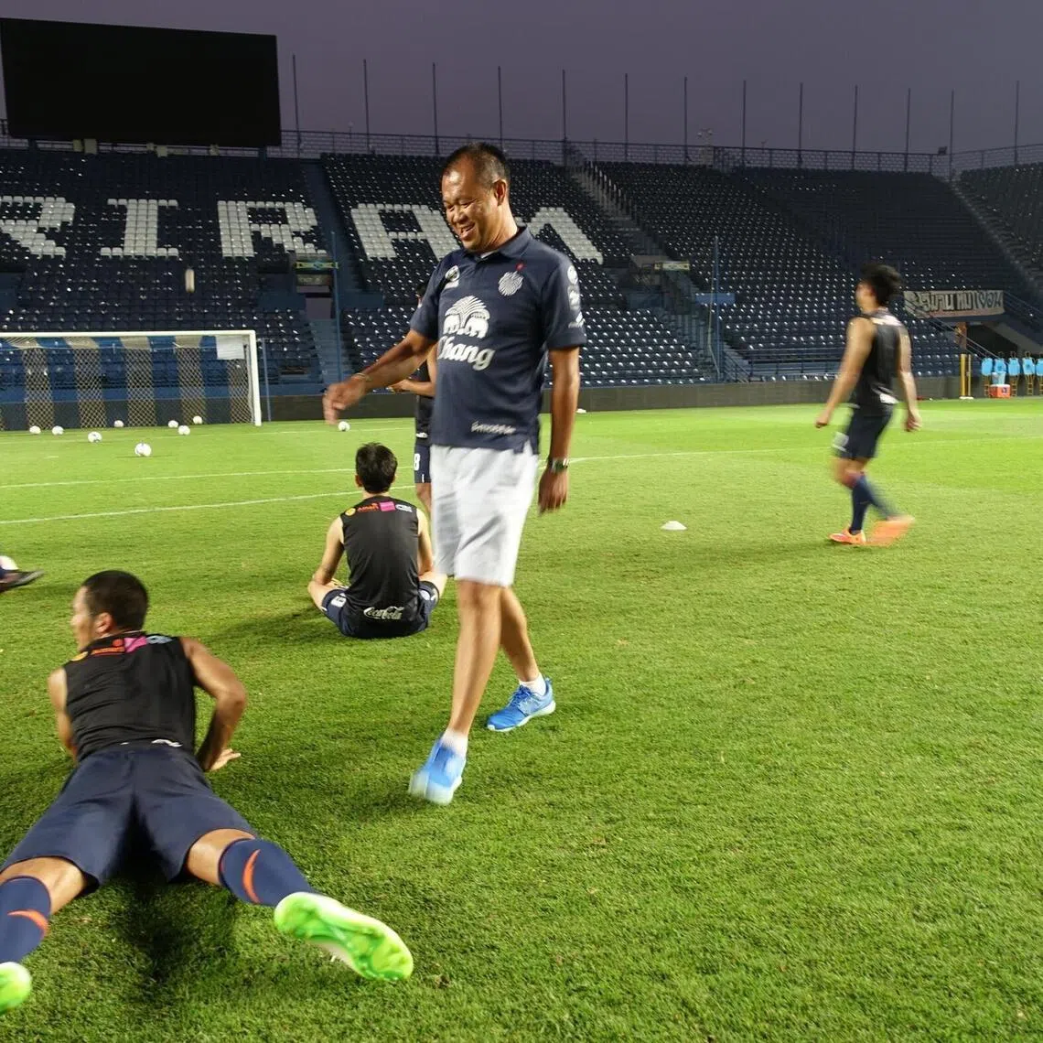 Mr Newin Chidchob (in blue shoes) hamming it up with footballers of Buriram United during a training session.