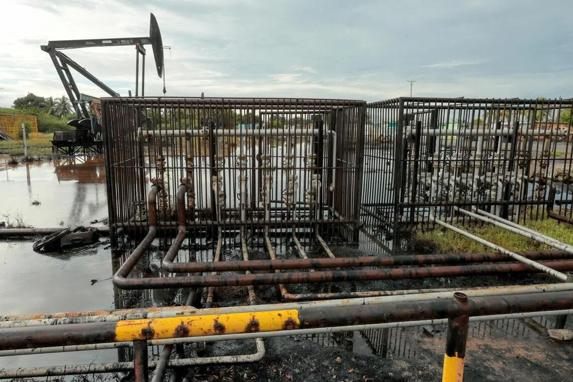 Pipelines and an oil pump jack are seen in an oil field near Lake Maracaibo in Venezuela. Most analysts believe oil prices will continue to fall through 2026 amid a global supply glut.