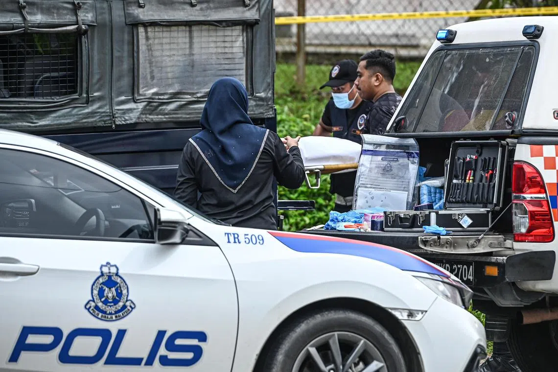 Police load onto a truck the body of a 65-year-old woman who was run over and stabbed in a town in Terengganu, Malaysia.